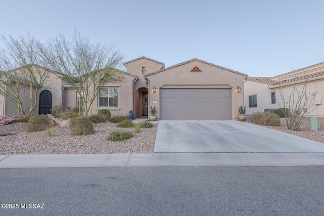 mediterranean / spanish home featuring driveway, an attached garage, a tile roof, and stucco siding