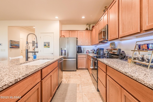 kitchen with light stone counters, stainless steel appliances, a sink, and recessed lighting