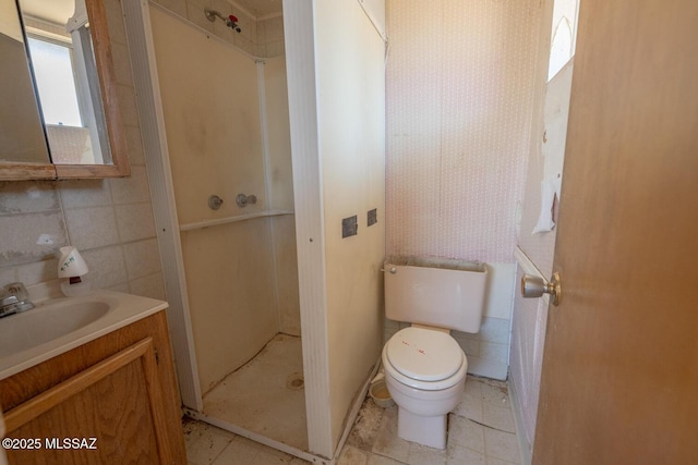 full bathroom with toilet, vanity, tile walls, a shower stall, and wallpapered walls