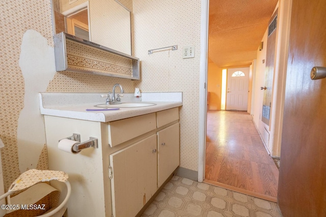 bathroom with visible vents, vanity, wallpapered walls, and tile patterned floors