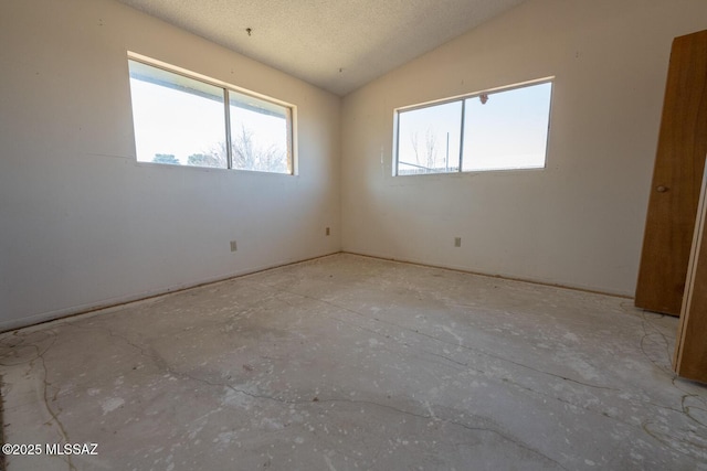 empty room with lofted ceiling and a textured ceiling