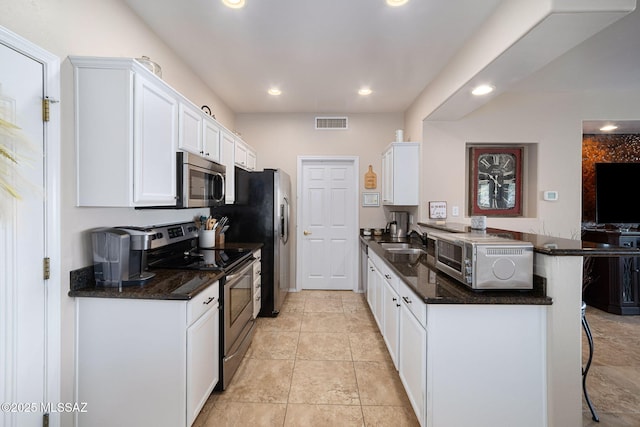 kitchen with visible vents, a kitchen bar, a peninsula, stainless steel appliances, and a sink