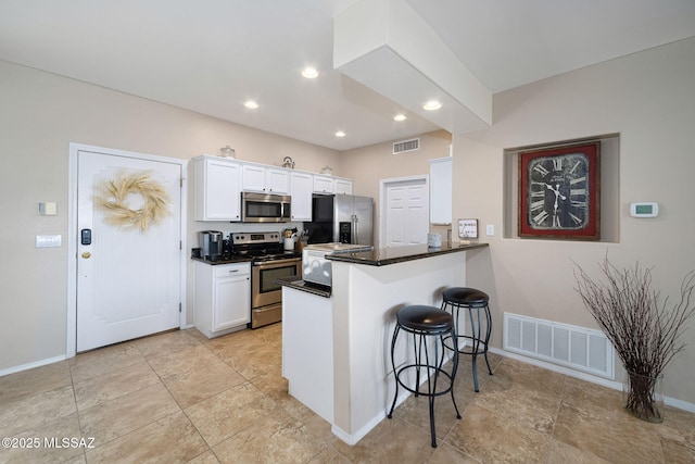 kitchen featuring a kitchen bar, visible vents, white cabinetry, and stainless steel appliances