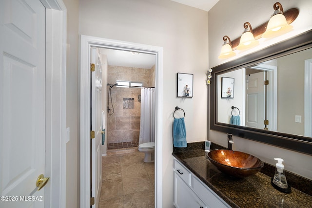 bathroom with tiled shower, toilet, and vanity