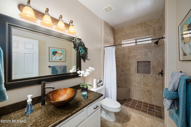 bathroom with vanity, toilet, visible vents, and tiled shower