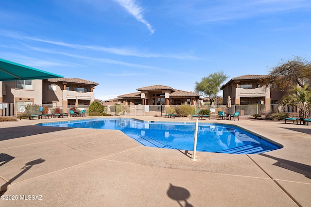 community pool with a patio area and fence