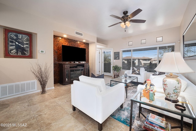 living room with baseboards, visible vents, and ceiling fan