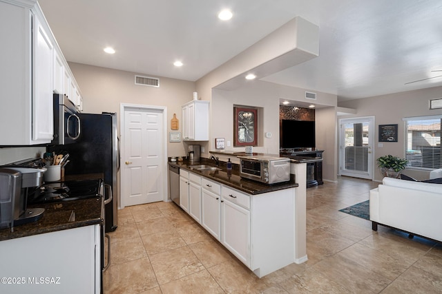 kitchen featuring visible vents, a peninsula, stainless steel appliances, white cabinets, and open floor plan