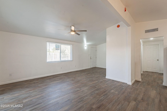 unfurnished room with dark wood-style floors, visible vents, ceiling fan, and baseboards