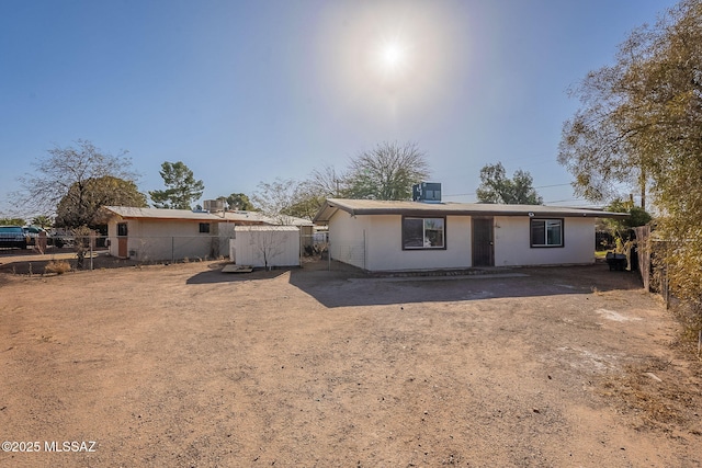 view of front of house featuring cooling unit, fence, and dirt driveway