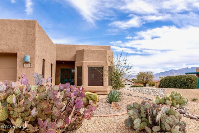 rear view of property with stucco siding and a mountain view