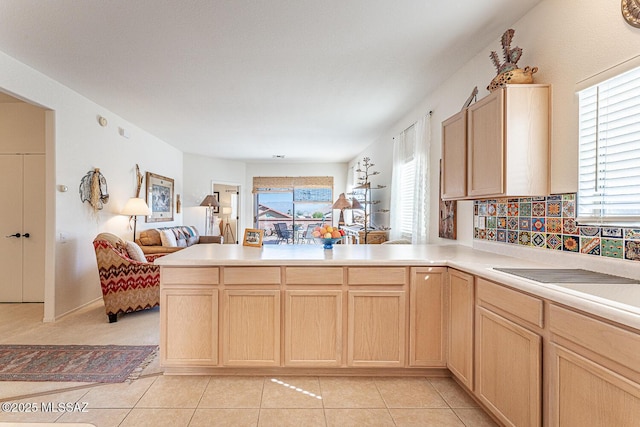 kitchen featuring light tile patterned floors, light brown cabinets, a healthy amount of sunlight, a peninsula, and open floor plan