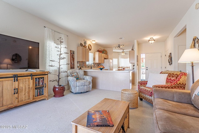 living area featuring visible vents, light carpet, and a ceiling fan