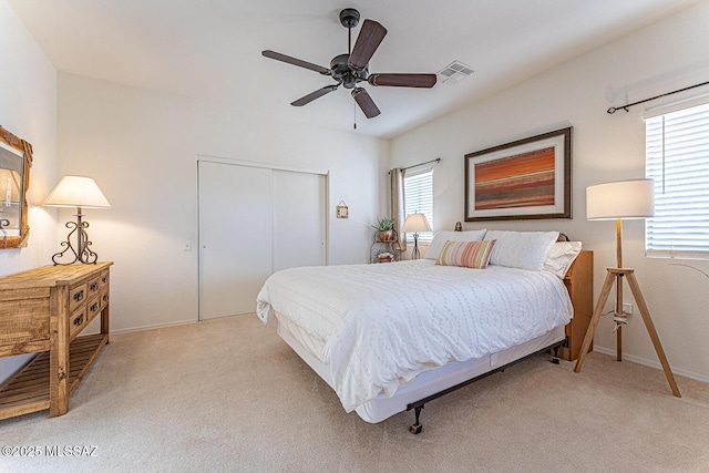 bedroom featuring visible vents, multiple windows, a closet, and light carpet