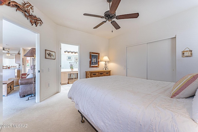 bedroom featuring light carpet, ensuite bath, a closet, and a ceiling fan