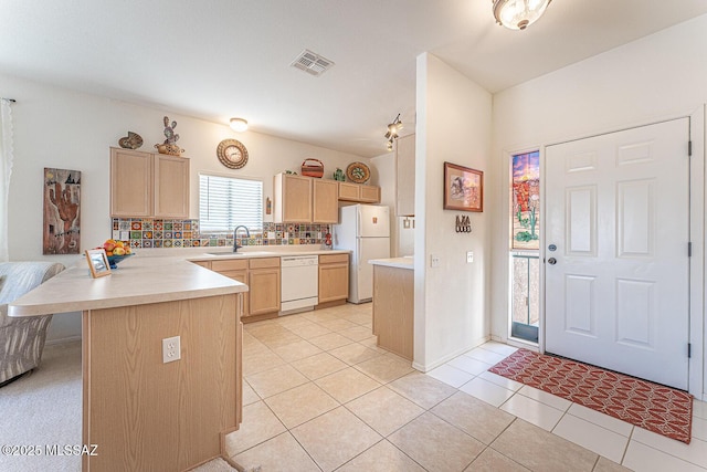 kitchen featuring light brown cabinetry, a sink, white appliances, a peninsula, and light countertops