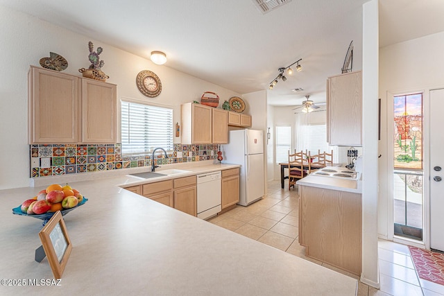 kitchen featuring light countertops, light tile patterned floors, decorative backsplash, white appliances, and a sink