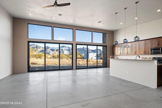 kitchen featuring finished concrete flooring, visible vents, glass insert cabinets, a towering ceiling, and stainless steel microwave