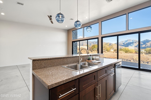 kitchen featuring visible vents, a kitchen island with sink, a sink, a mountain view, and dishwasher