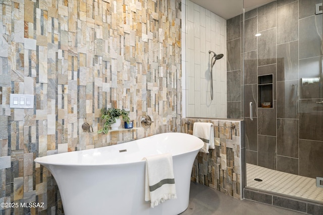 full bath featuring a freestanding tub, tiled shower, and tile walls