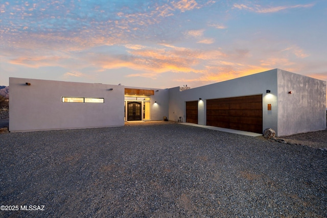 pueblo-style house with stucco siding, a garage, and driveway