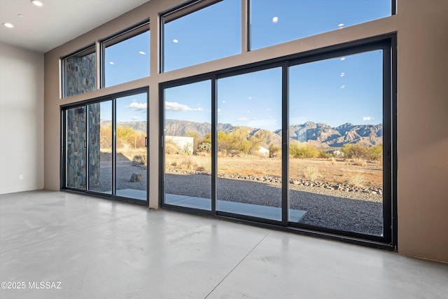 doorway to outside with recessed lighting, a mountain view, concrete floors, and a high ceiling