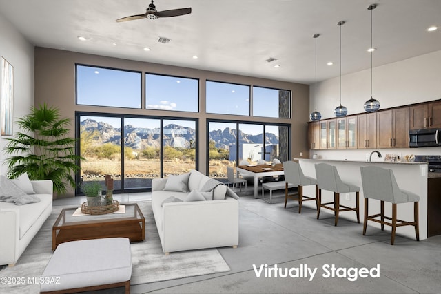 living area with visible vents, plenty of natural light, concrete flooring, and a towering ceiling