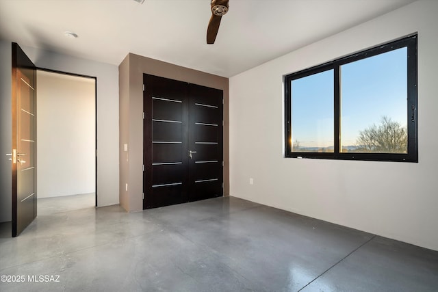 unfurnished bedroom featuring a closet, concrete floors, and a ceiling fan