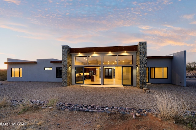 back of house at dusk with stucco siding