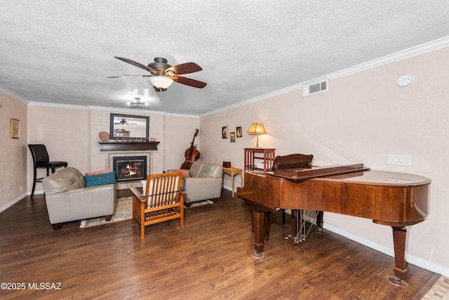 sitting room with wood finished floors, visible vents, ceiling fan, a glass covered fireplace, and crown molding