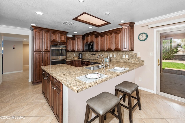 kitchen featuring backsplash, appliances with stainless steel finishes, a peninsula, and a sink