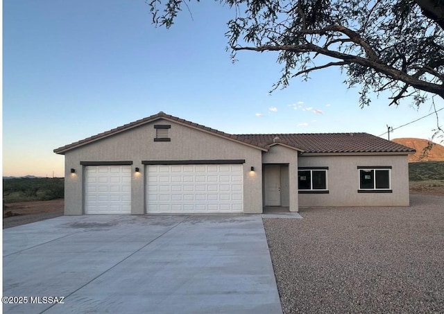 single story home with a garage, driveway, a tile roof, and stucco siding