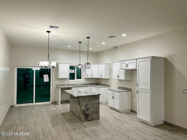 kitchen with light wood-type flooring, a center island, white cabinetry, and visible vents