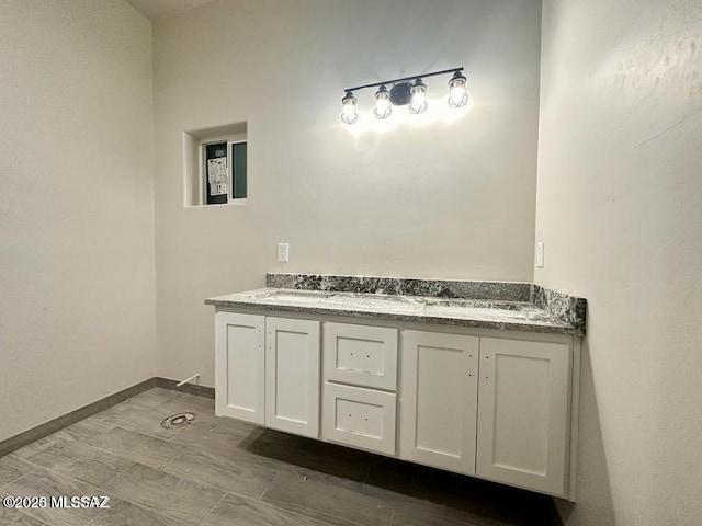 bathroom featuring double vanity, a sink, and baseboards