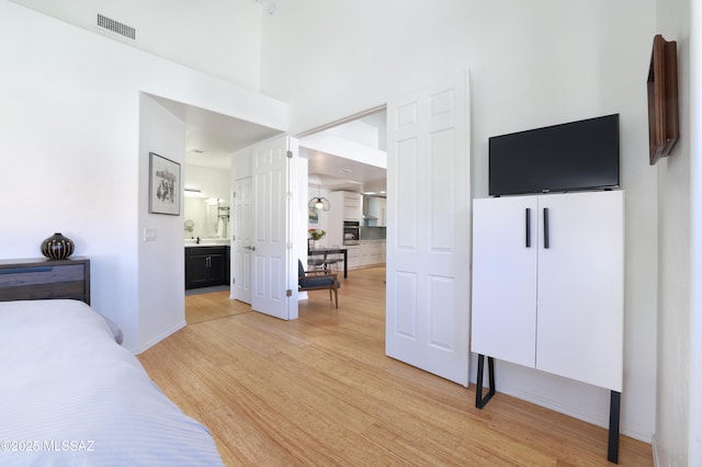 bedroom featuring a closet, visible vents, light wood-style flooring, and ensuite bathroom