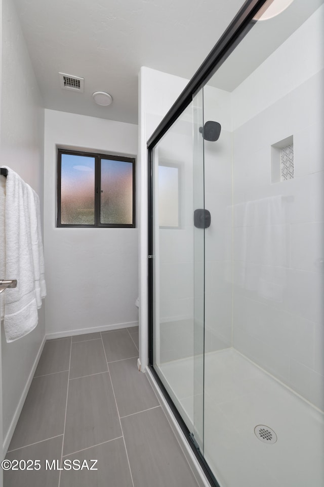 full bathroom featuring toilet, visible vents, baseboards, tile patterned floors, and a stall shower