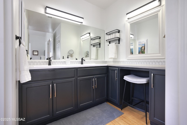 full bathroom featuring double vanity, a sink, and wood finished floors