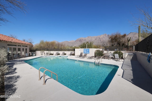 pool with fence, a mountain view, and a patio