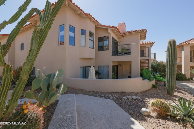 back of house featuring a tiled roof and stucco siding