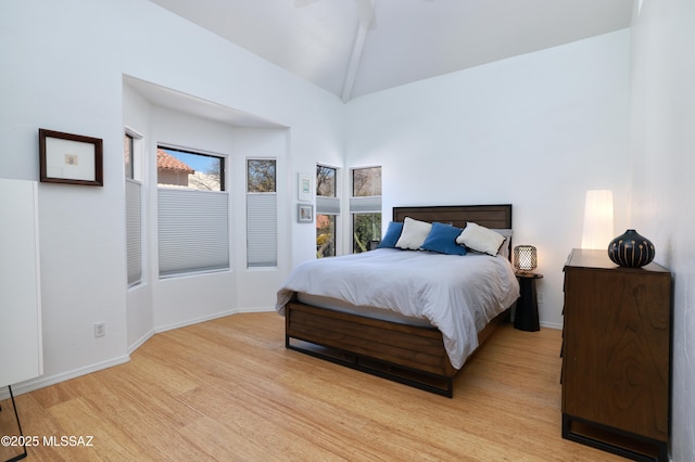 bedroom featuring vaulted ceiling, light wood-type flooring, and baseboards