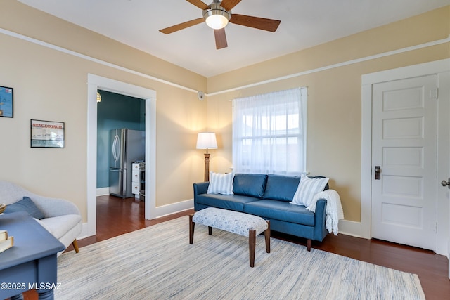 living room with a ceiling fan, baseboards, and wood finished floors