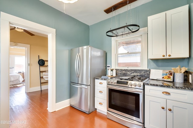 kitchen with dark stone counters, appliances with stainless steel finishes, light wood-style flooring, and white cabinetry