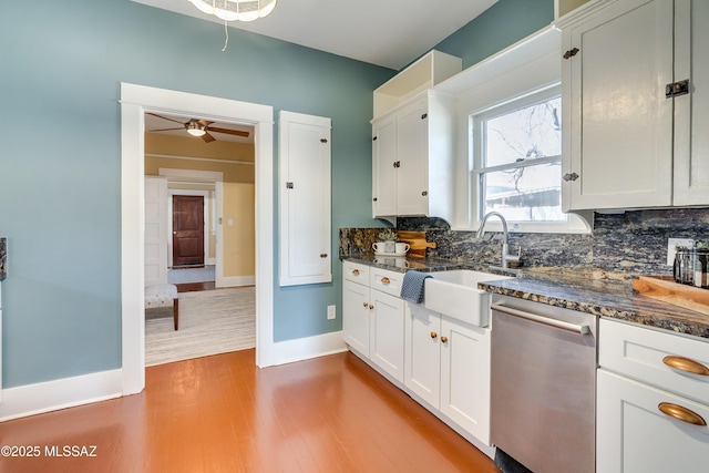 kitchen featuring a sink, white cabinets, stainless steel dishwasher, light wood-type flooring, and decorative backsplash