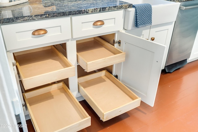 details featuring dark countertops, white cabinets, stainless steel dishwasher, and wood finished floors