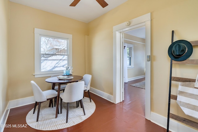 dining space featuring dark wood-type flooring, ceiling fan, and baseboards