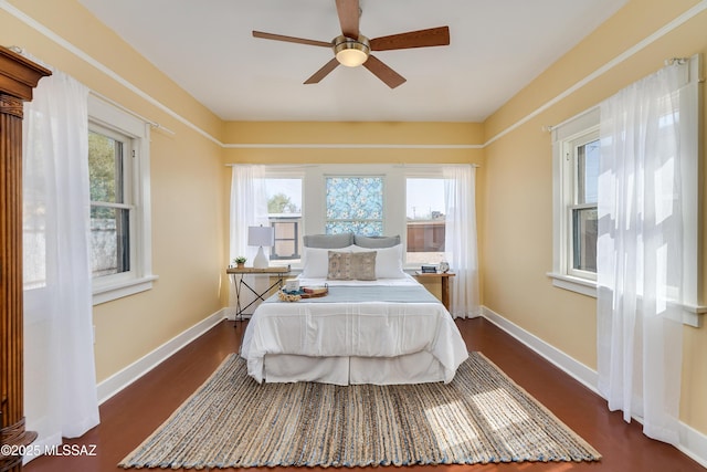 bedroom with dark wood-type flooring, ceiling fan, and baseboards