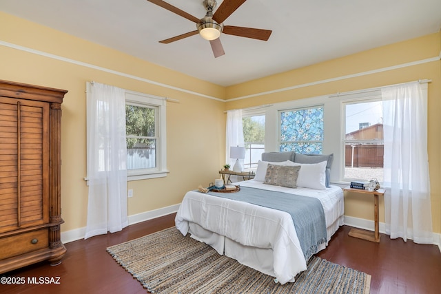 bedroom with multiple windows, wood finished floors, a ceiling fan, and baseboards