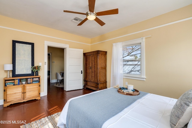 bedroom featuring a ceiling fan, baseboards, visible vents, and wood finished floors