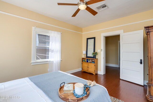 bedroom featuring dark wood-style floors, ceiling fan, visible vents, and baseboards