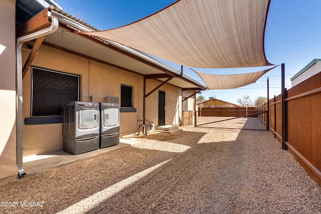 view of side of home with fence, washing machine and clothes dryer, and stucco siding